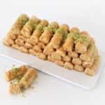 Baklava rolls with flaky phyllo pastry, cashew filling, and sweet syrup drizzle on a plate