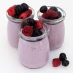 Blueberry panna cotta in small glass jars topped with berries