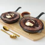 skillet brownie topped with cream and dusted with powdered sugar