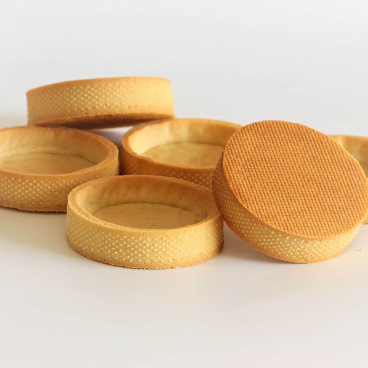 Golden baked sweet shortcrust pastry tart shells (pâte sablée) with crisp edges and smooth bases ready for filling
