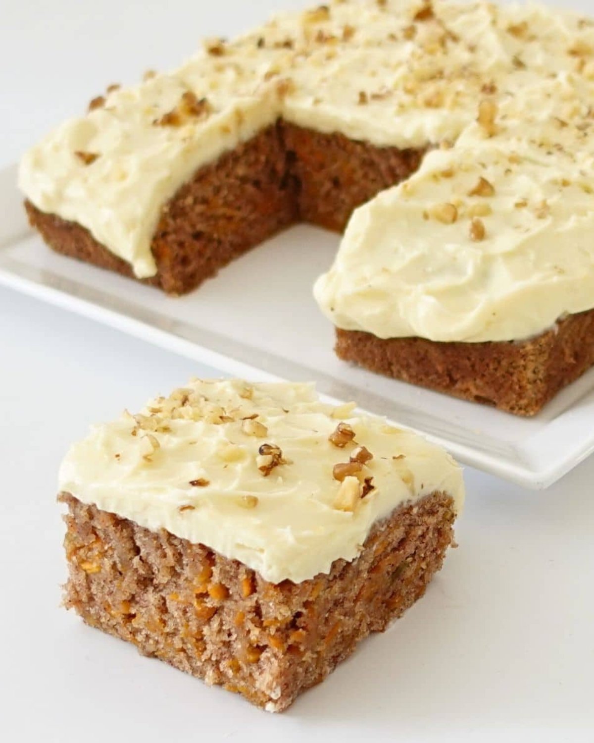 Eggless carrot cake topped with creamy frosting and chopped walnuts