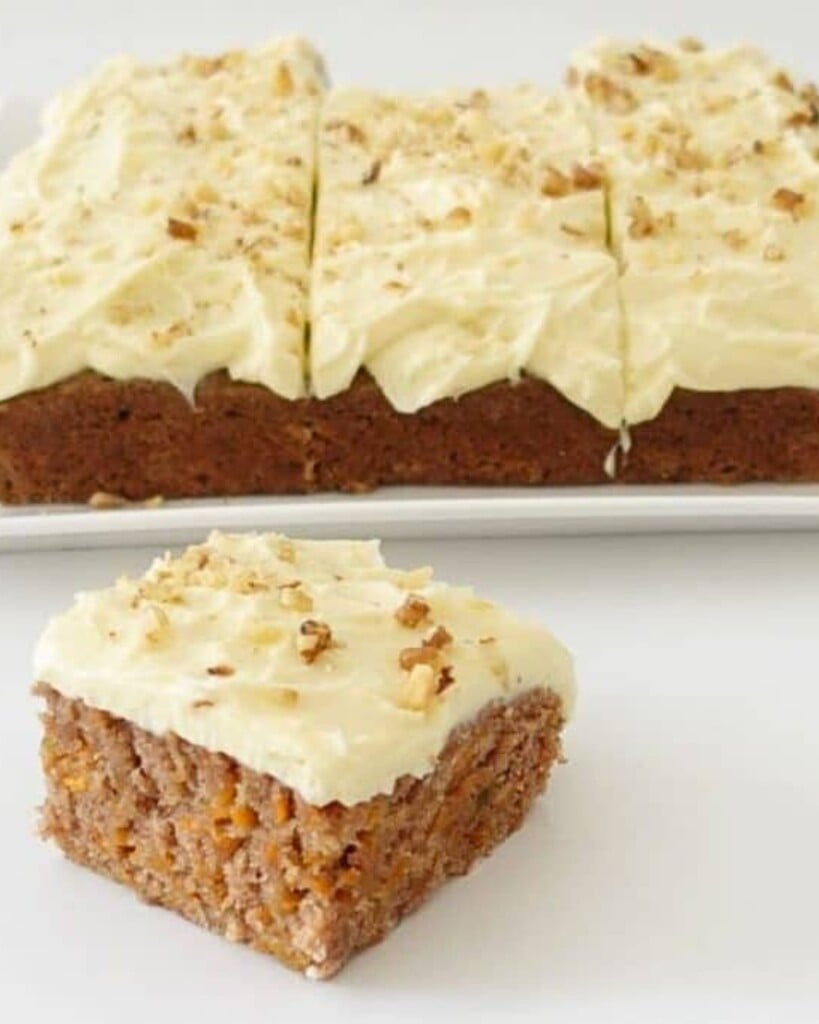 A slice of eggless carrot cake showing soft texture and creamy frosting