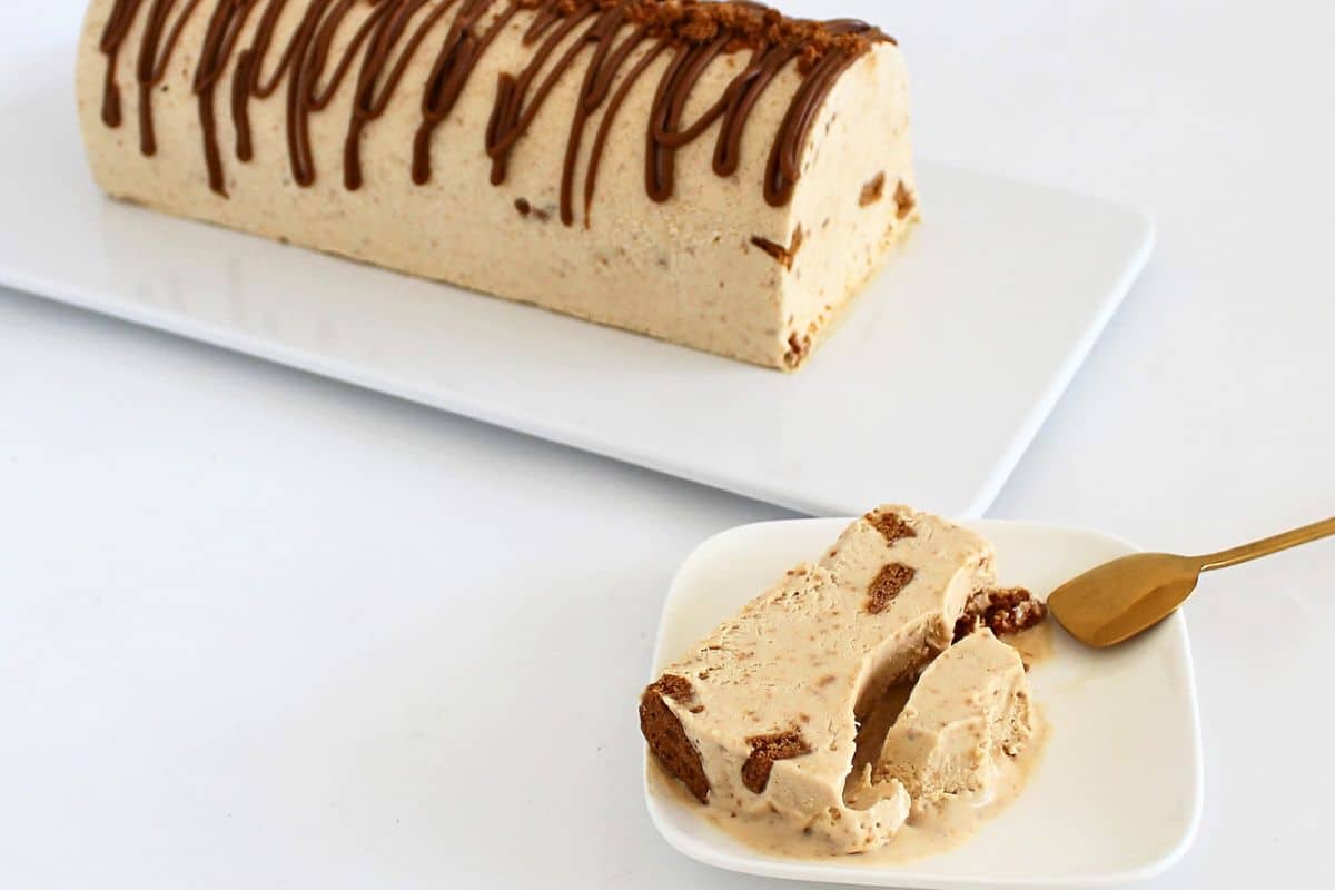 Slice of Biscoff ice cream log showing cookie butter swirls and Biscoff crumbs on a white plate