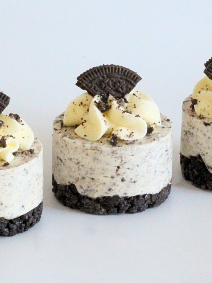 Mini Cookies and Cream Cheesecakes topped with whipped cream and Oreo pieces