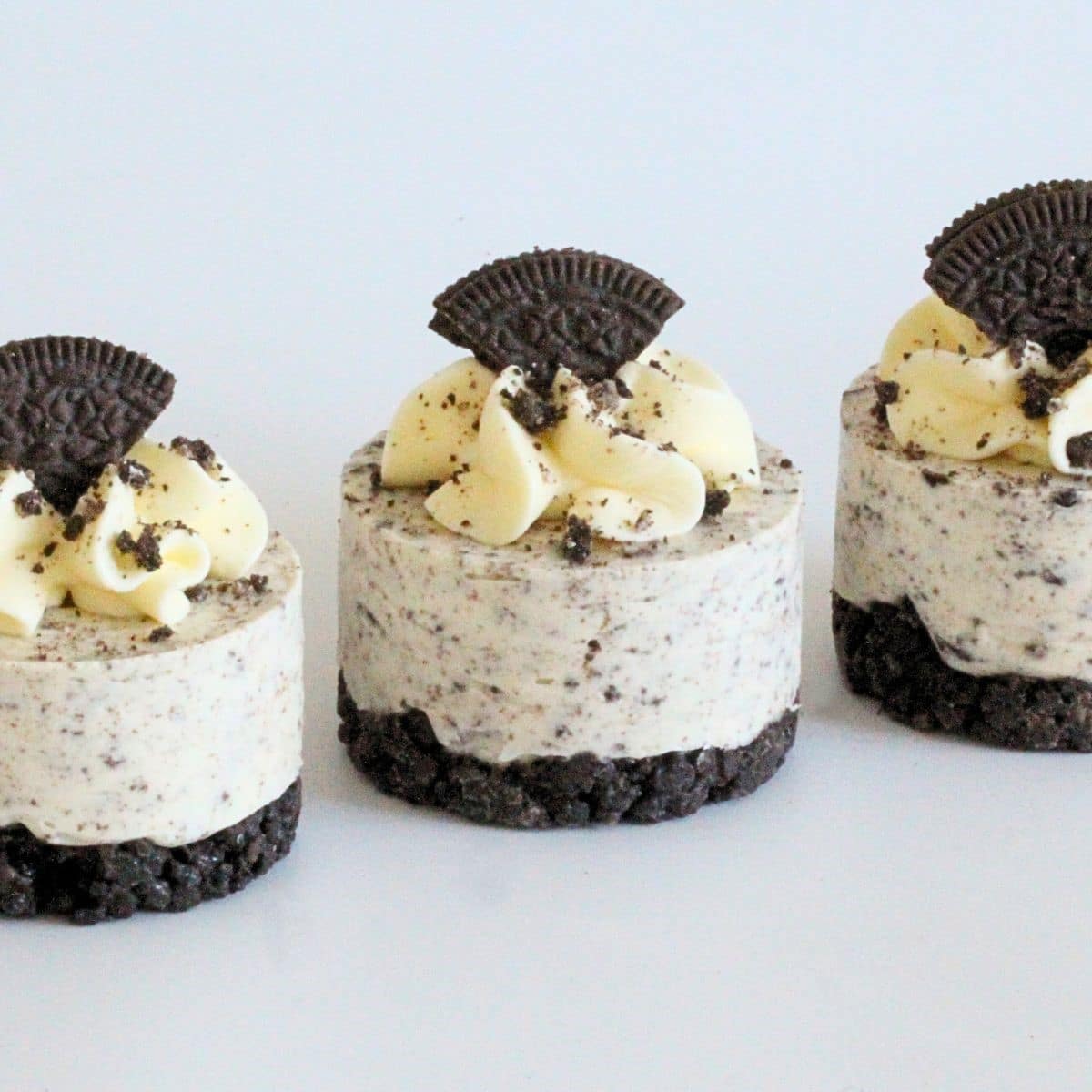 Mini Cookies and Cream Cheesecakes topped with whipped cream and Oreo pieces