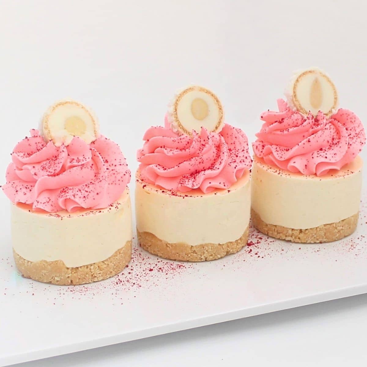 Mini coconut cheesecakes topped with pink whipped cream and Raffaello chocolates