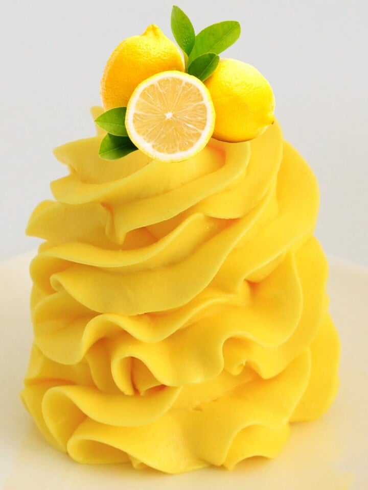 Lemon curd buttercream piped in tall ruffled swirls, topped with a fresh lemon slice and mint leaves