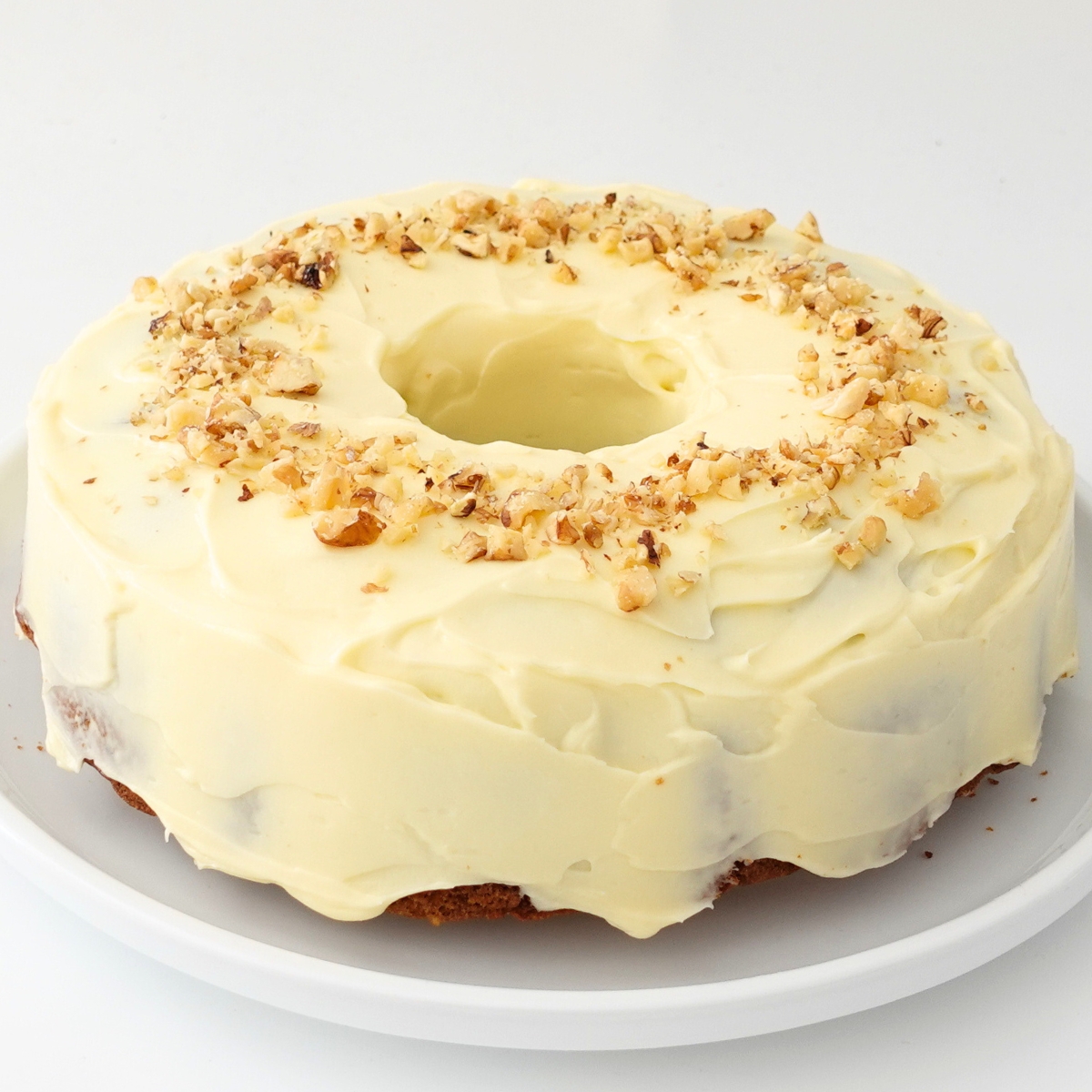 Finished moist carrot cake topped with smooth cream cheese frosting and extra walnuts