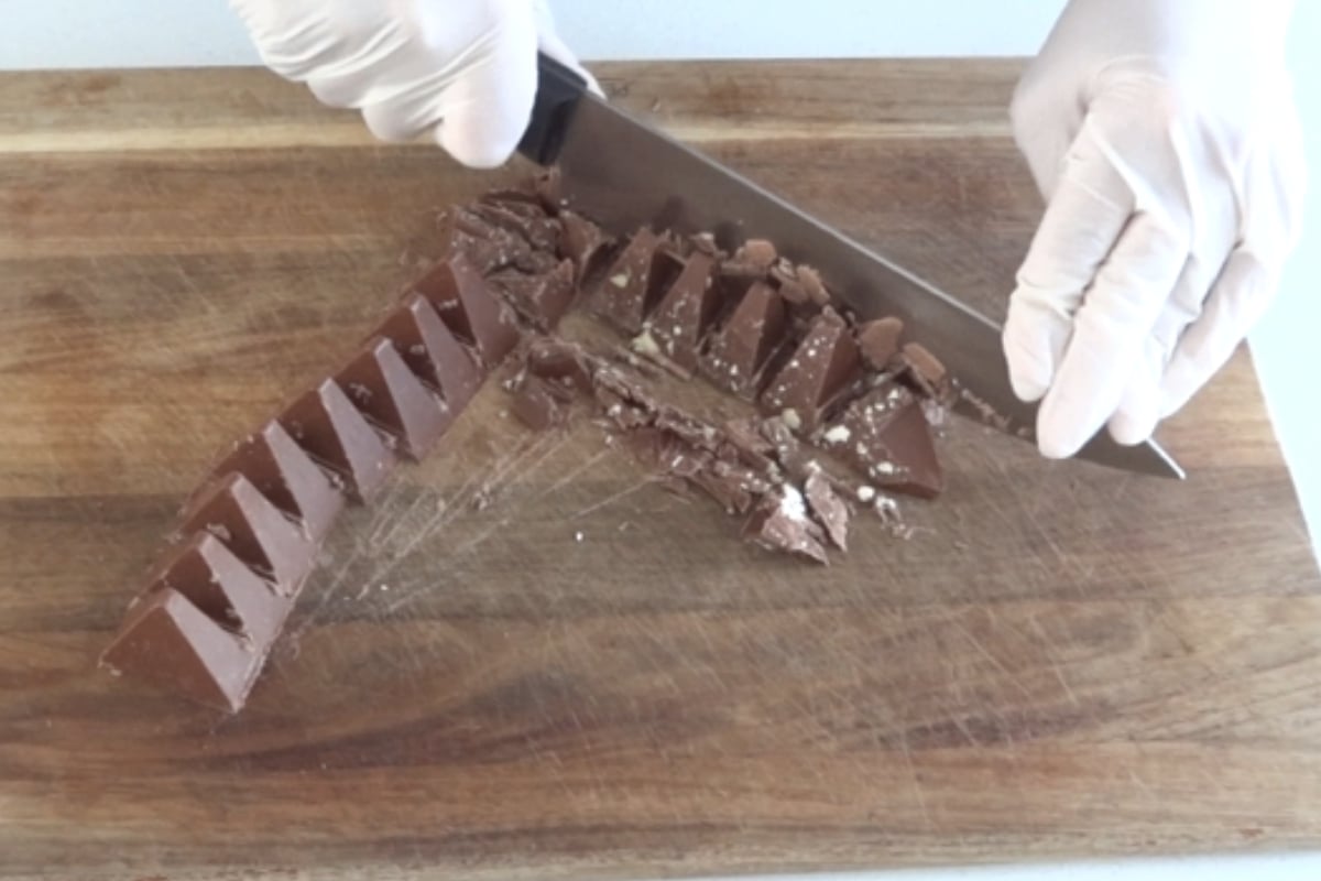 Close up of Toblerone triangles chopped on a wooden board for dessert cups