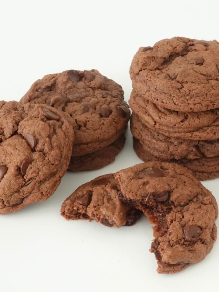 Stack of chocolate cake mix cookies with one cookie broken in half showing melty chocolate chips and chunks inside