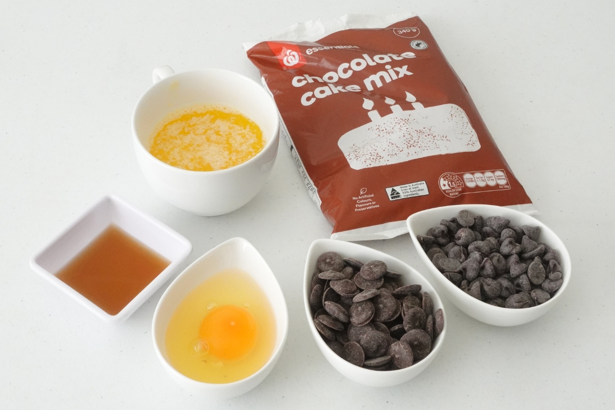 Overhead shot of ingredients for chocolate cake mix cookies with cake mix, egg, unsalted butter, chocolate chips, and chocolate chunks