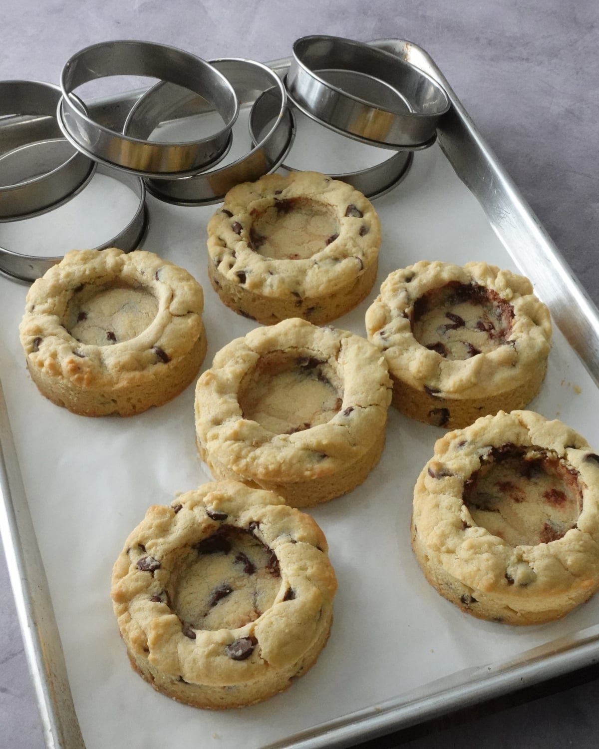 Baked Nutella deep dish cookies on a tray with pressed wells ready to fill with Nutella