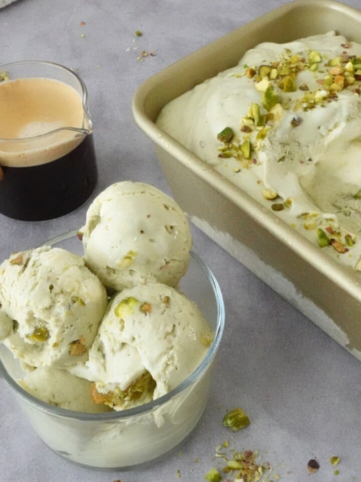 Bowl of creamy pistachio ice cream with chopped pistachios beside a loaf pan filled with ice cream and an espresso shot for affogato