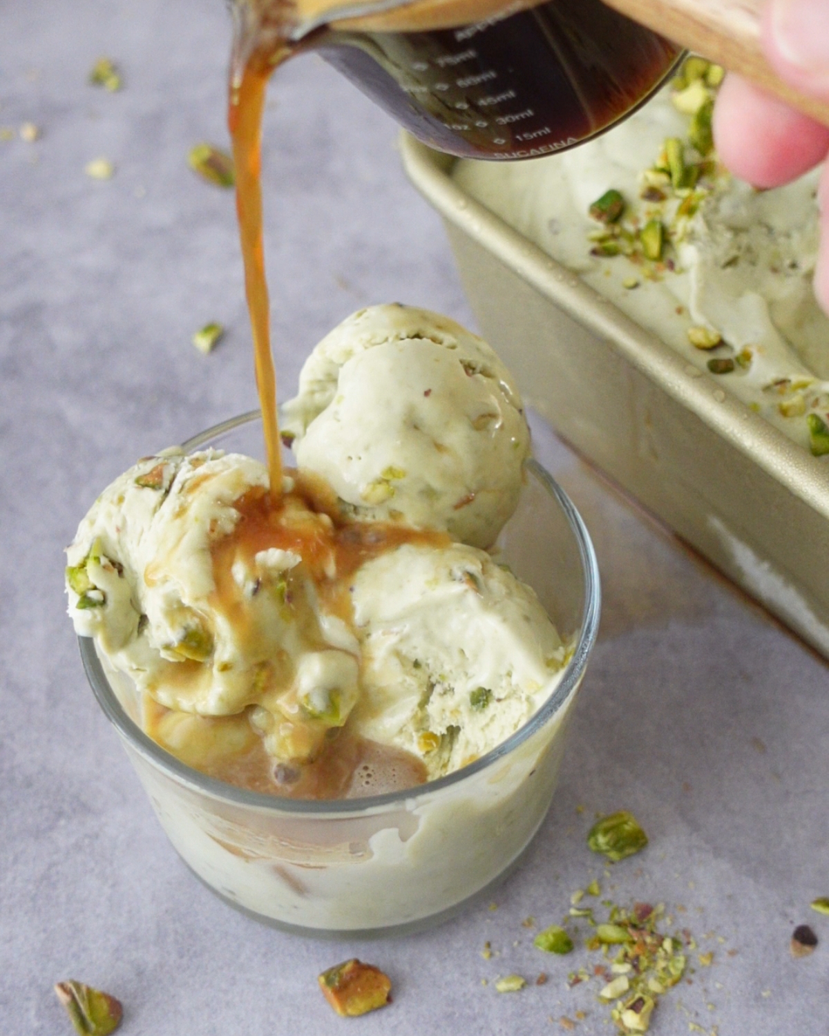 Pouring hot espresso over pistachio ice cream in a glass for an affogato dessert