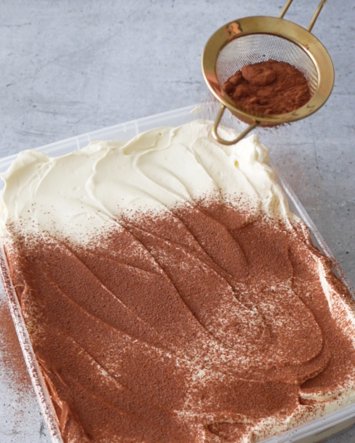 dusting cocoa powder over tiramisu cheesecake topping before serving