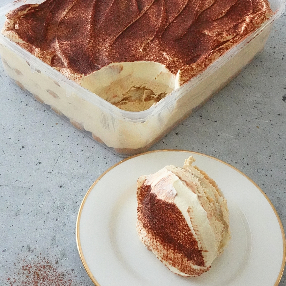 Tiramisu cheesecake in a tray topped with cocoa powder and creamy layers