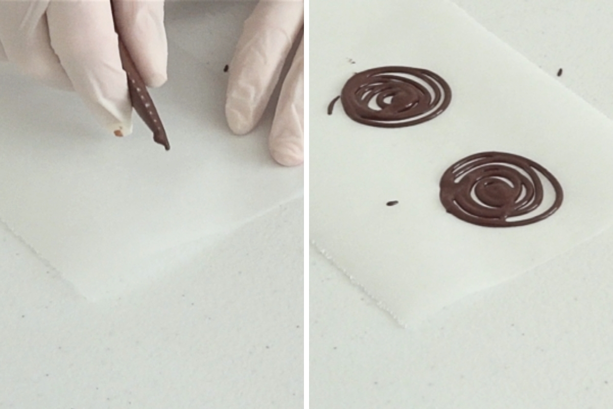 Piping melted chocolate into thin spiral shapes on parchment paper to create decorations for mini pumpkin cheesecakes