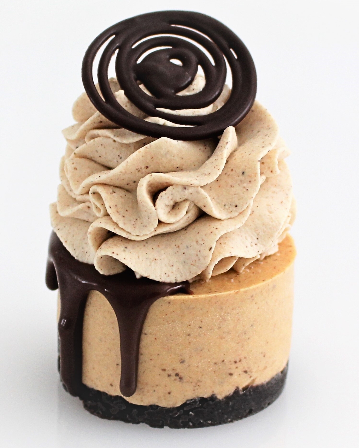 Mini pumpkin cheesecake with a chocolate drip, pumpkin spice cream swirl, and a set chocolate topper on a clean background