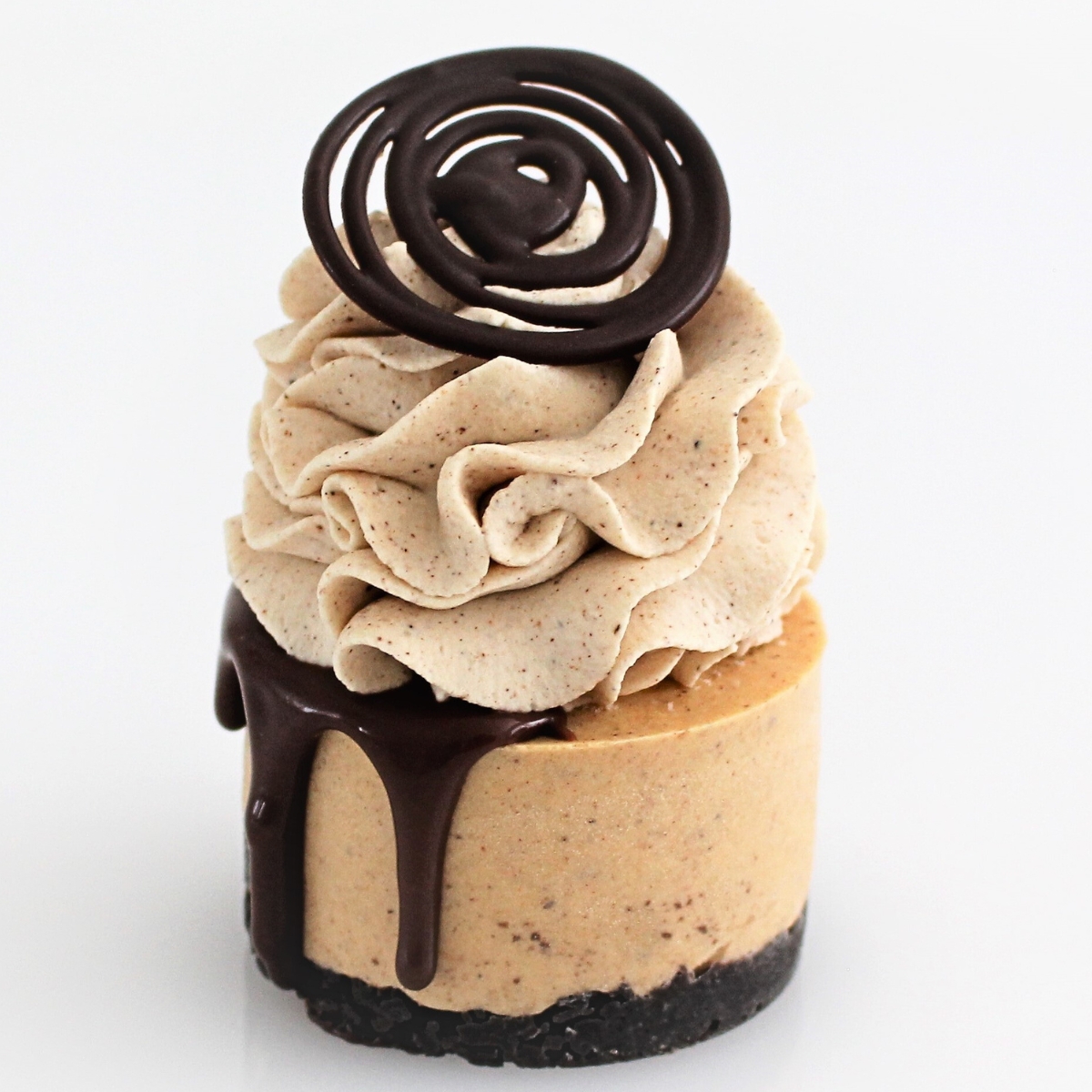 Mini pumpkin cheesecake with a chocolate drip, pumpkin spice cream swirl, and a set chocolate topper on a clean background