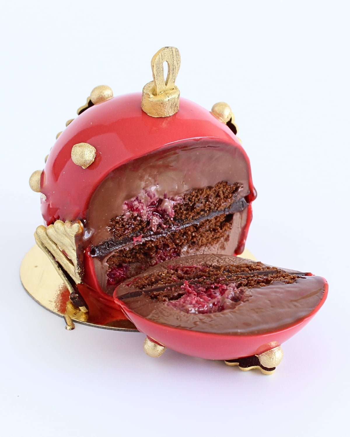 Cut red chocolate ornament showing raspberry and chocolate layers.