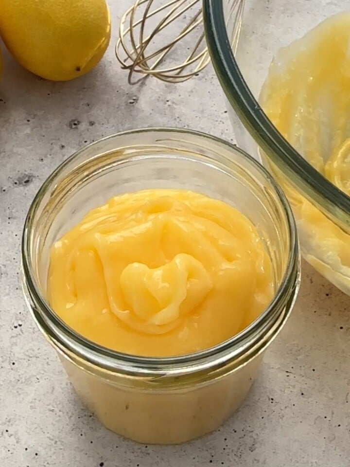 Whole Egg Lemon Curd in a glass jar, fresh lemons beside it