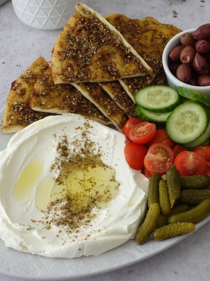 Labneh dip recipe on a platter with za'atar, olive oil, and fresh vegetables