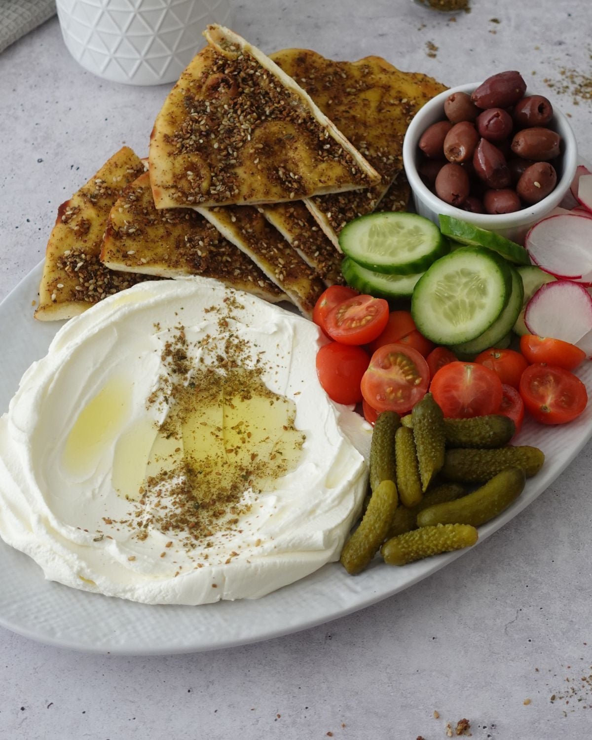 Labneh dip recipe on a platter with za'atar, olive oil, and fresh vegetables