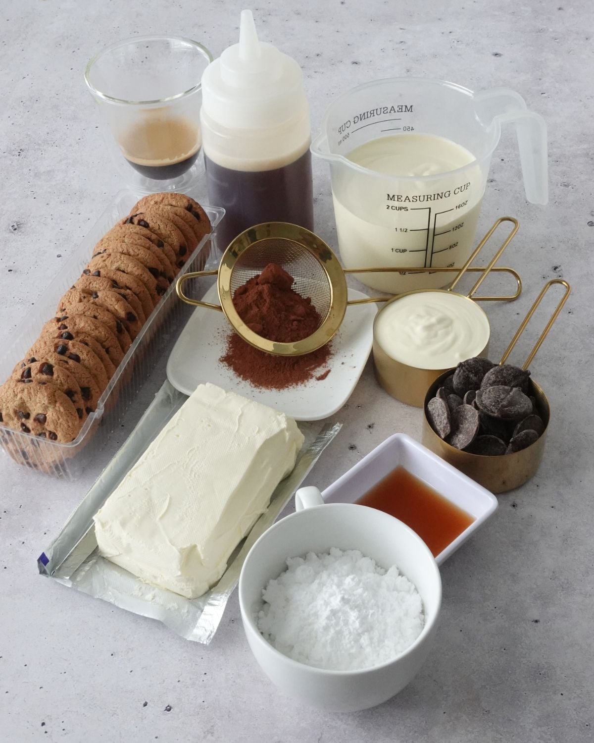 Tiramisu ingredients including cream cheese, chocolate chip cookies, cocoa powder, coffee, heavy cream, and chocolate