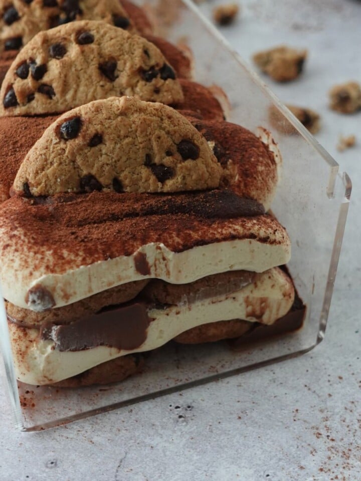 No-bake chocolate chip tiramisu cheesecake in a loaf pan, layered with cocoa powder and topped with chocolate chip cookies