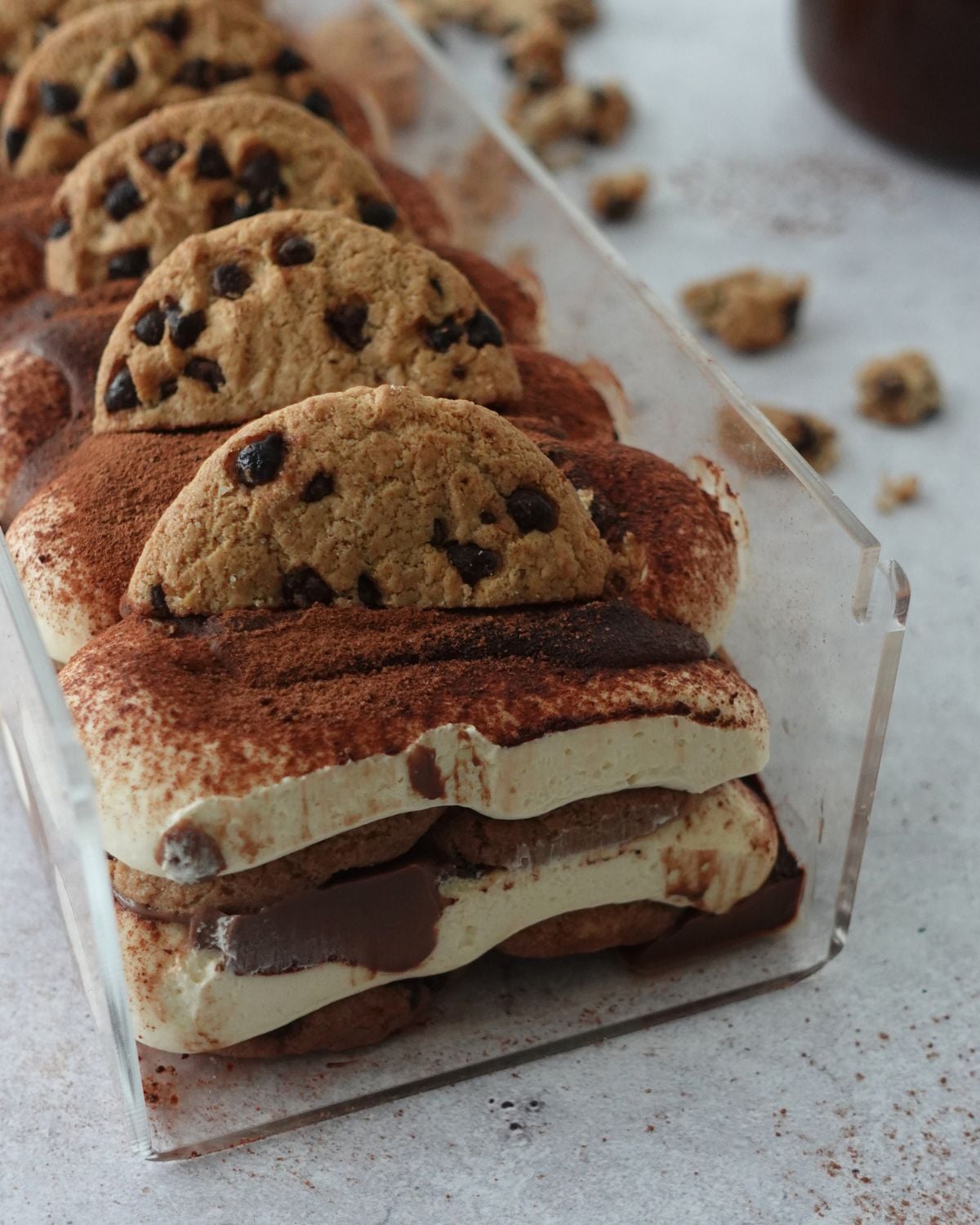 No-bake chocolate chip tiramisu cheesecake in a loaf pan, topped with chocolate chip cookies and dusted with cocoa powder