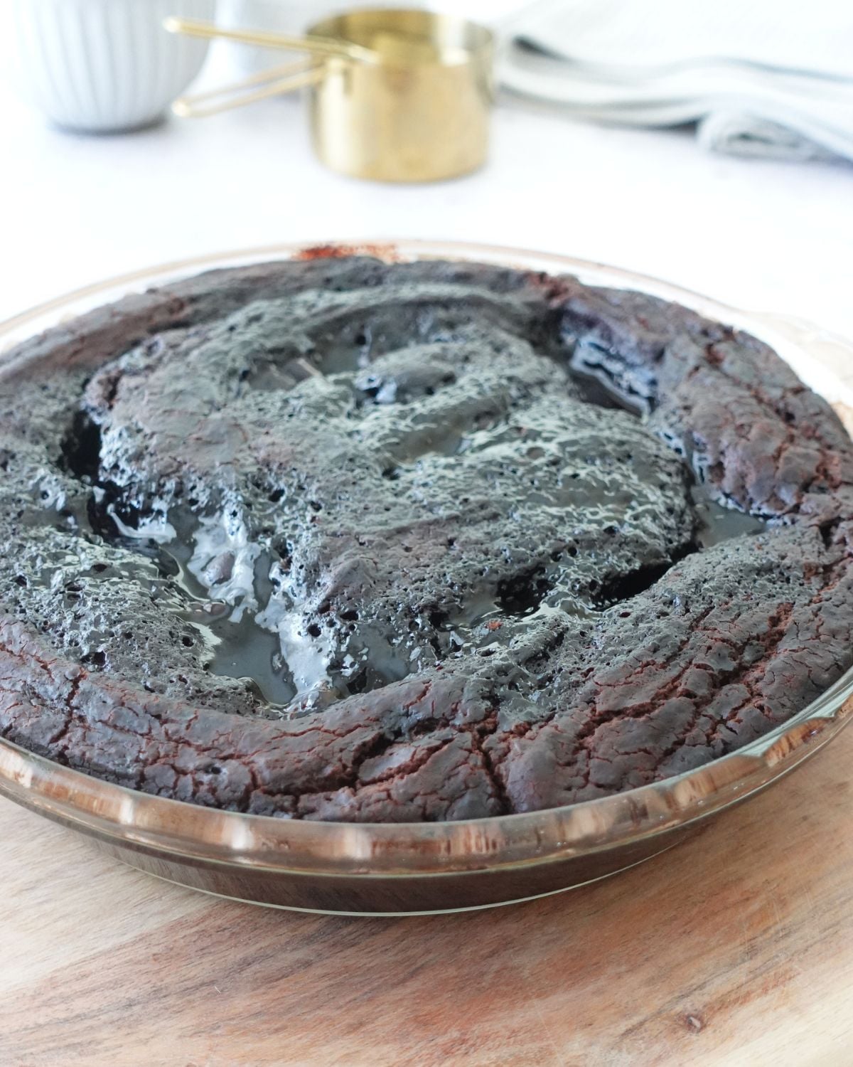 Baked chocolate self saucing pudding cooling in a pie dish on a wooden board