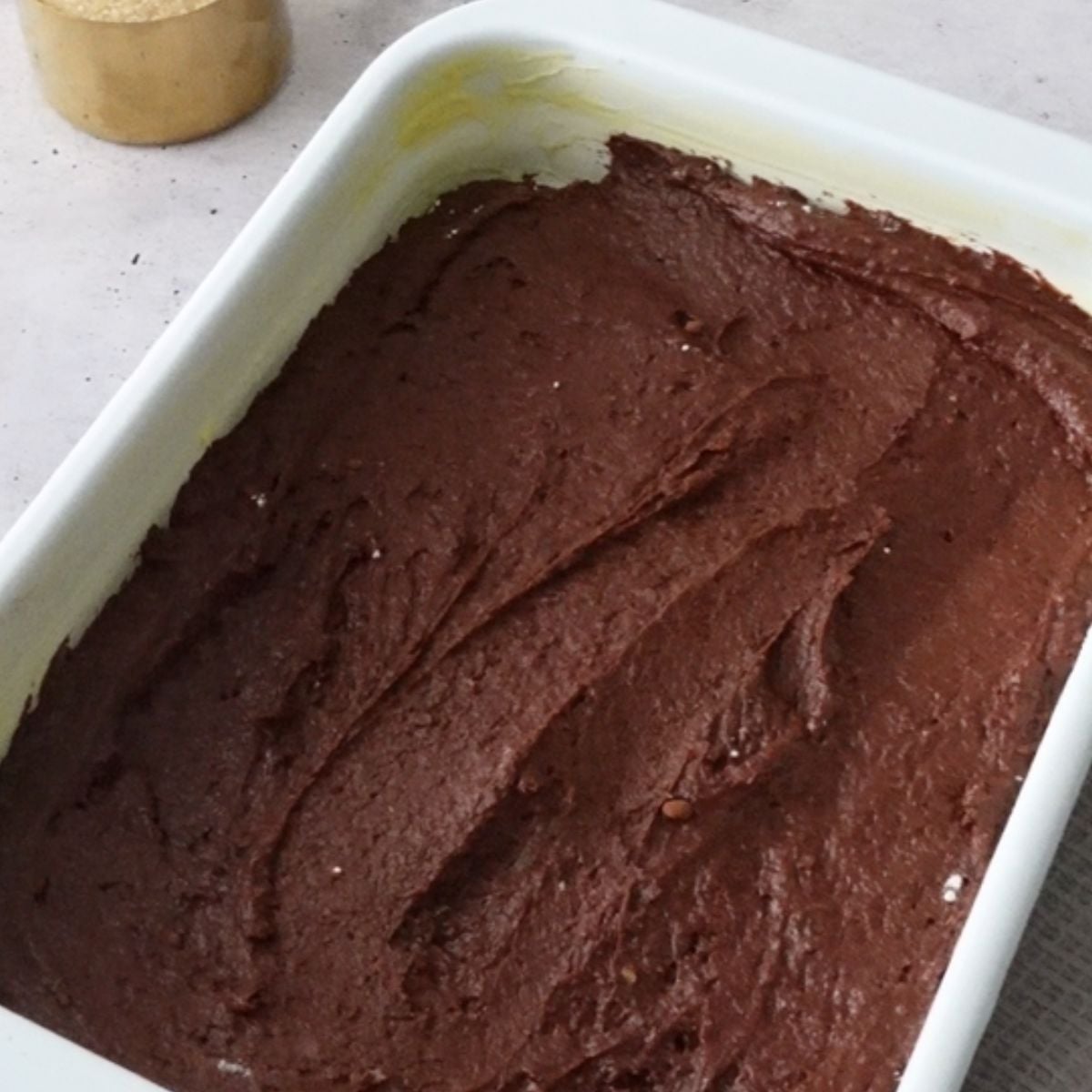 Chocolate pudding batter spread into a white baking dish