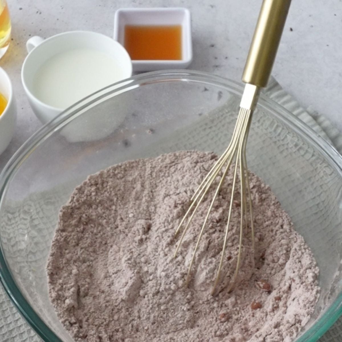Dry chocolate cake ingredients whisked together in a glass bowl
