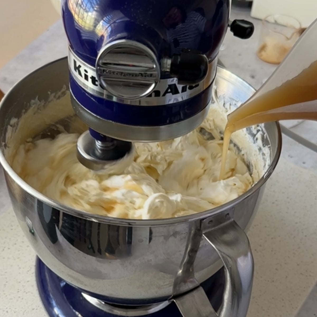 Dissolved sugar and espresso mixture being poured into whipped butter for coffee hot water buttercream