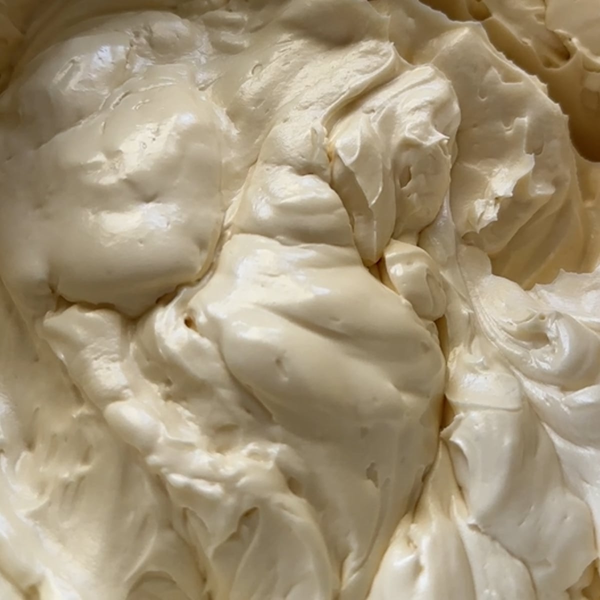 Finished coffee hot water buttercream, smooth and glossy in a stand mixer bowl