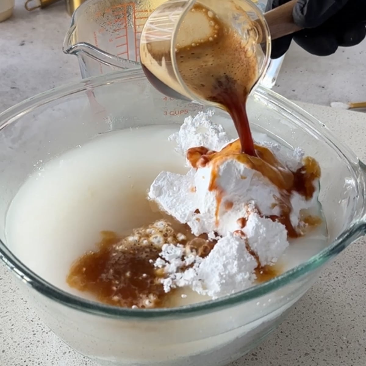 Brewed espresso being poured over powdered sugar and hot water for coffee hot water buttercream