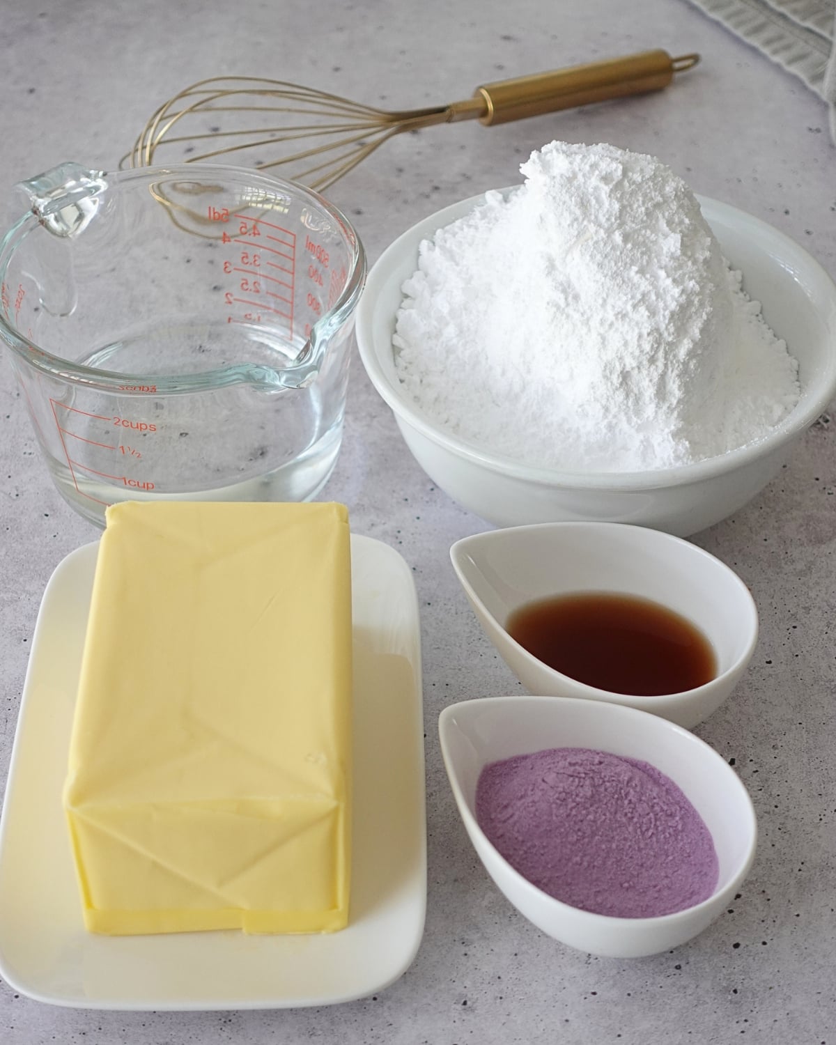 Ingredients for ube hot water buttercream: butter, powdered sugar, ube powder, vanilla, and hot water