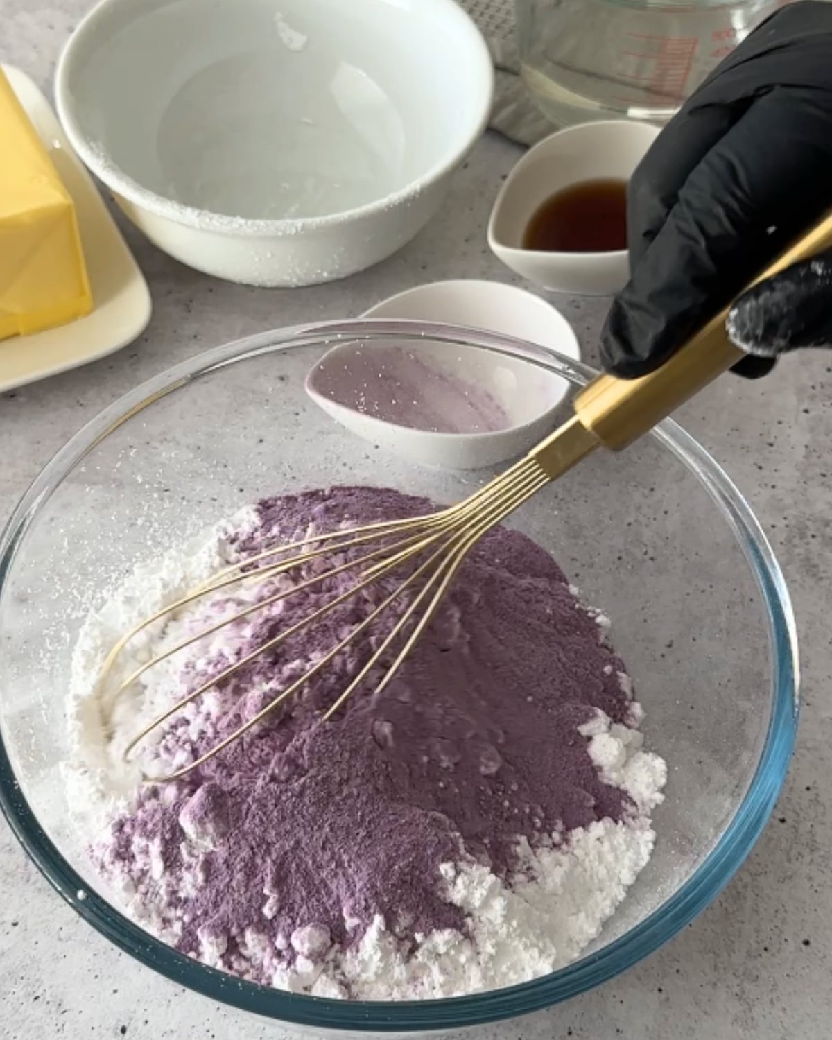 Whisking powdered sugar and ube powder together in a bowl