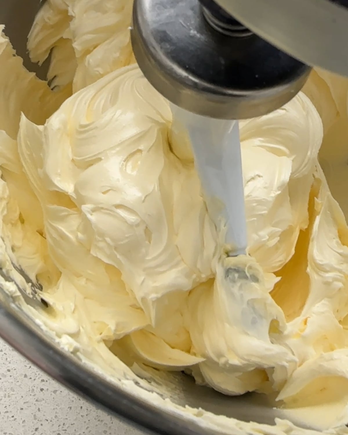 Whipped butter, pale and fluffy, in a stand mixer bowl
