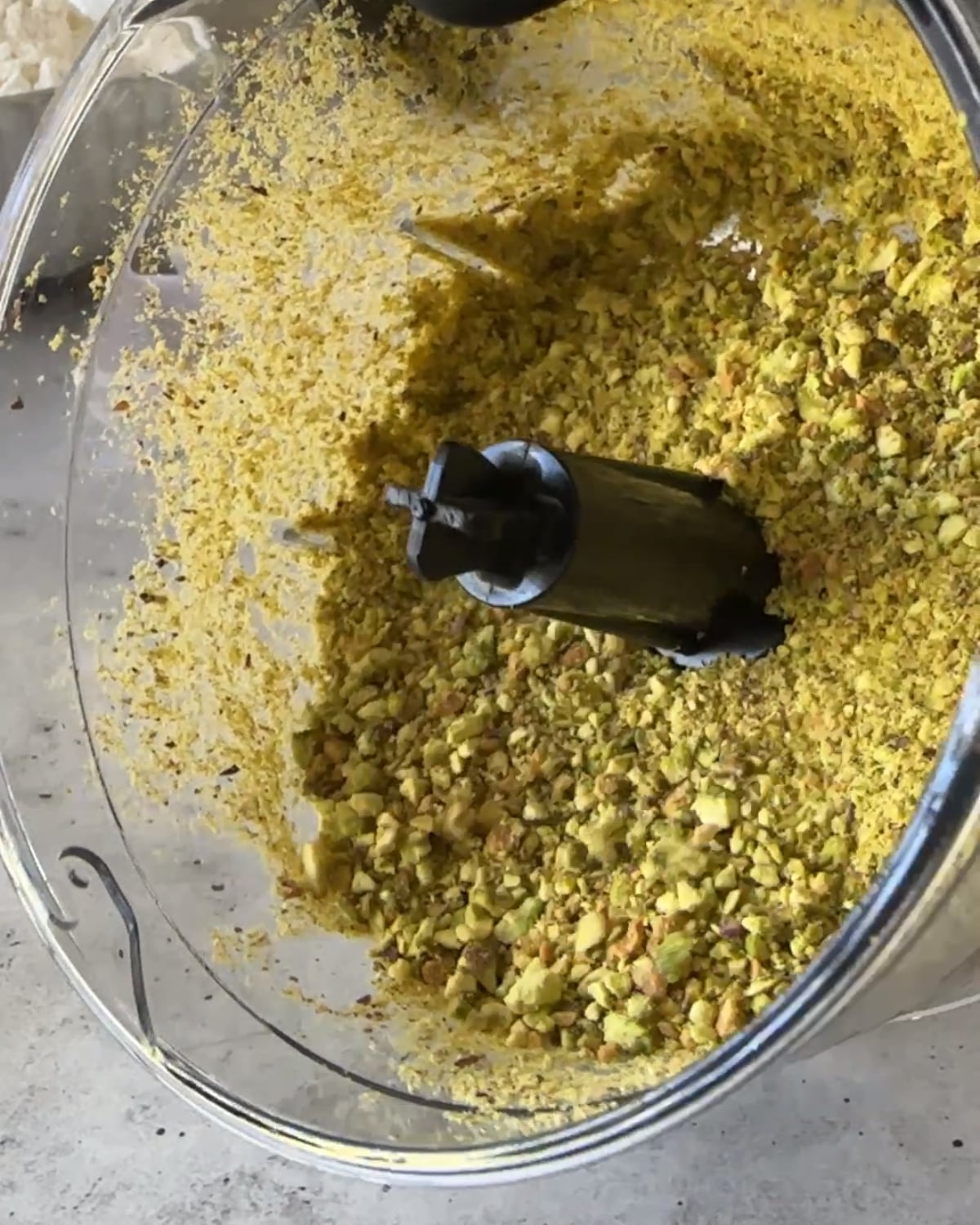 Crushed pistachios in a chopper bowl after blitzing