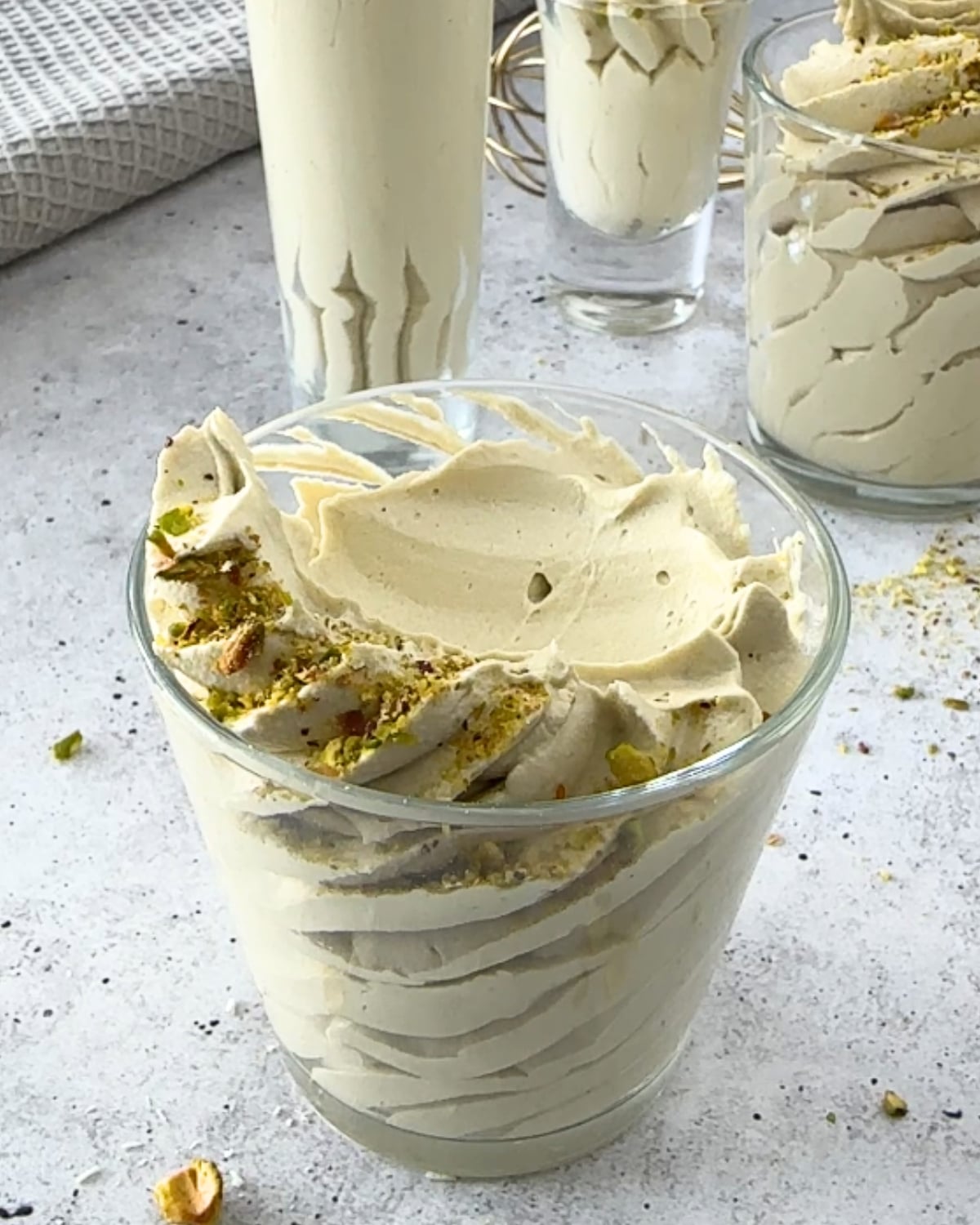 airy mousse topped with chopped pistachios, beside a glass of piped mousse