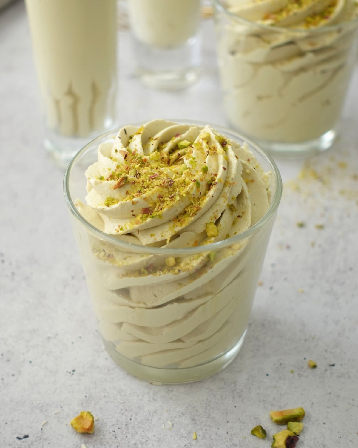 Glasses of pistachio mousse piped in tall swirls and sprinkled with chopped pistachios